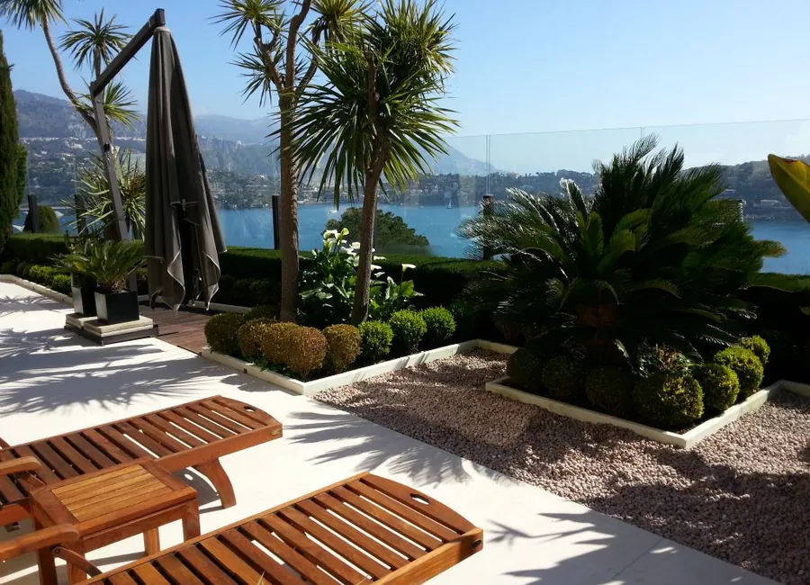 Jardin méditerranéen avec terrasse, palmiers et vue mer